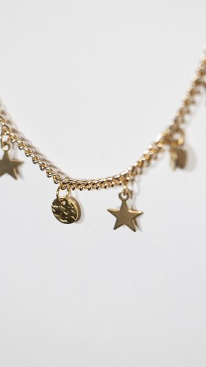 Detalle del collar Andrómeda en acero inoxidable dorado con estrellas y placas redondas